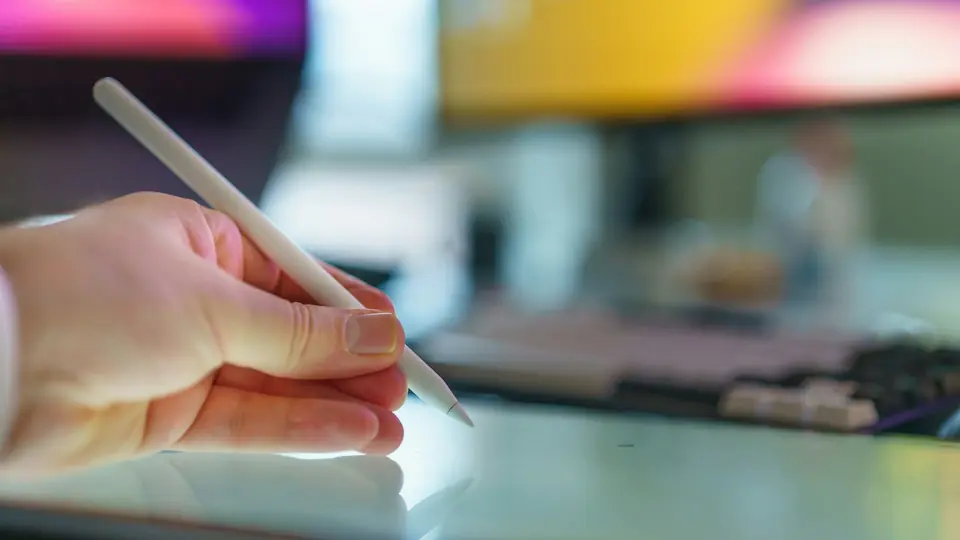A hand holds a stylus above a tablet, contextual photography for an article about image editing tools.